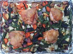 chicken, carrots and other vegetables on an aluminum foil sheet in a baking dish