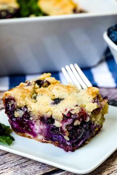 a slice of blueberry cobbler on a white plate with a fork next to it