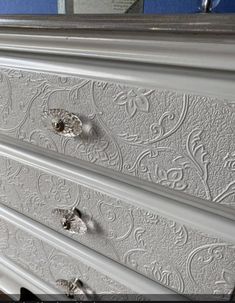 an ornate white dresser with drawers and knobs