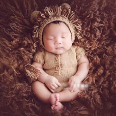 a newborn baby wearing a lion costume is laying on a brown fur covered blanket with his eyes closed