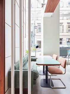 a room with a couch, table and chairs in it next to a wall that has multiple windows