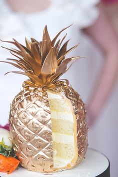 a pineapple shaped cake sitting on top of a white table next to strawberries