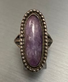 A beautiful vintage piece available for sale!  This unique vintage ring is set with a genuine opaque cabochon amethyst. This ring is a finger size 6 3/4 and weighs 8.6 grams. This ring will be shipped promptly in a gift pouch. We purchased a large estate of Vintage Silver Jewelry that I will be adding to our shop in the coming weeks, please keep coming back to view the new additions. Vintage Oval Cabochon Gemstones, Vintage Round Cabochon Gemstones, Collectible Oval Cabochon Amethyst Ring, Vintage Oval Moonstone Ring Hallmarked, Vintage Oval Cabochon Moonstone Ring, Vintage Moonstone Oval Cabochon Ring, Vintage Oval Gemstones For Gift, Vintage Jewelry With Natural Stones For Anniversary, Vintage Natural Stones Jewelry For Anniversary