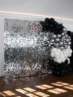 black and white balloons are hanging on the wall in front of a mirror paneled backdrop