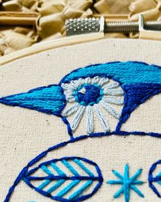 a close up of a blue bird on a piece of cloth with stitches and thread