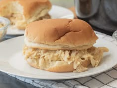 a chicken sandwich on a white plate next to a bowl of macaroni and cheese