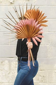 a woman is holding up a fake palm leaf