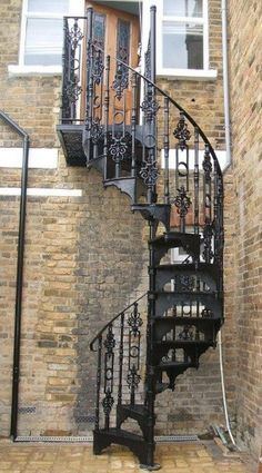 a spiral staircase in front of a brick building with wrought iron railings and doors