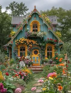 a green house with lots of flowers on the front door and windows in the roof