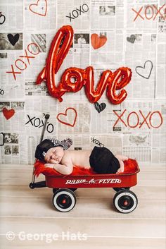 a baby laying in a wagon with the word love spelled on it