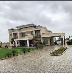 a large house sitting in the middle of a lush green field next to a parking lot