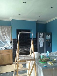 a kitchen with blue walls and wooden ladders in the foreground, next to a stove