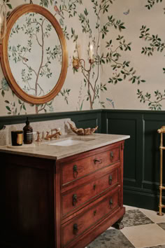 a bathroom with green walls and wallpaper has a wooden vanity topped with a marble counter top