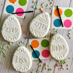 three decorated cookies sitting on top of a wooden table next to confetti sticks