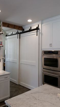 a kitchen with white cabinets and marble counter tops, stainless steel appliances and an island