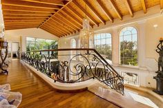 an ornate staircase in a large home with wood flooring and ceiling beams, along with chandelier