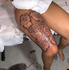 a woman's leg with flowers on it and the word tattoo written in cursive writing