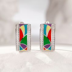 Designed to enhance the lifestyle of the modern woman, these dazzling earrings reflect the latest jewelry fashion trends. Shining brightly with panels of multicolored enamel, these radiant sterling silver earrings glisten with white round-cut stones. With a myriad of colours everywhere, why not add some to your jewelry box with beautiful enamel jewelry. Treat yourself or surprise her with this piece.Carat Weight: 0.56 ctStone Size: 1 mmStone Type: Jeulia® StoneNumber of Stones: 56 Stone Shape: R Modern Multicolor Earrings With Bold Design, Elegant Rainbow Hoop Earrings, Modern Multicolor Enamel Jewelry, Modern Multicolor Sterling Silver Earrings, Multicolor Sterling Silver Earrings For Anniversary, Silver Enamel Earrings For Anniversary, Dazzling Earrings, Jewelry Fashion Trends, Classy Jewelry