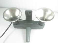 two shiny metal balls on top of a white table next to a corded phone