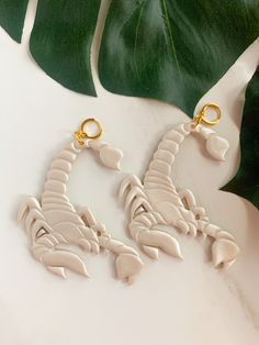 two white scorpion earrings with gold accents