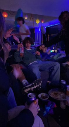 group of people sitting on couches in a room with blue lights and food around them