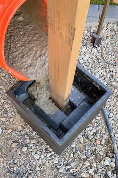 the cement is being poured onto the ground by a large orange bucket with water coming out of it