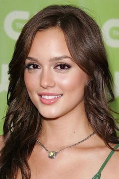 a close up of a person wearing a green dress and smiling at the camera with long brown hair