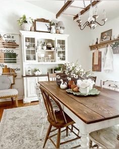 a dining room table and chairs in front of a white hutch filled with potted plants