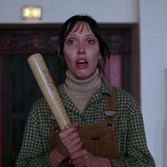 a woman holding a large baseball bat in her right hand and making a funny face