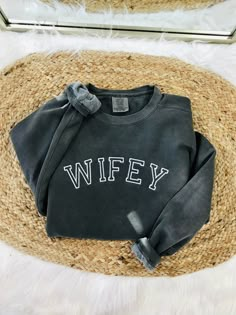 a sweater with the word wife written on it sitting on a rug next to a mirror