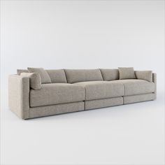 a long couch with pillows on it in front of a white wall and grey floor