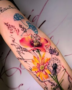 a colorful tattoo with flowers and butterflies on the left side of the arm that has writing all over it