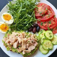 a white plate topped with meat and veggies next to an egg on top of lettuce