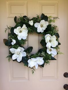 a wreath with white flowers and greenery hangs on the front door