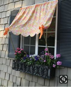 the window is decorated with flowers and an orange bow hanging from it's valance