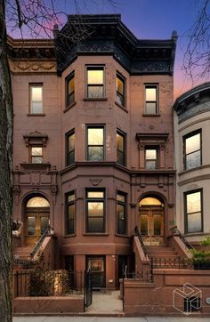 an apartment building with many windows and steps leading up to the front door at dusk