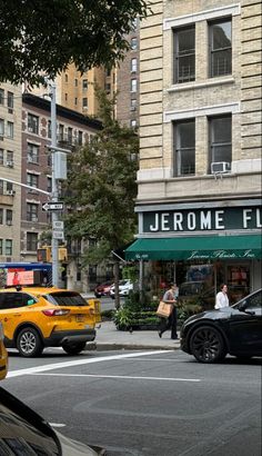 cars are driving down the street in front of a store with people walking on it