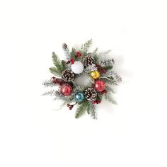 a christmas wreath with ornaments hanging from it's side on a white wall background