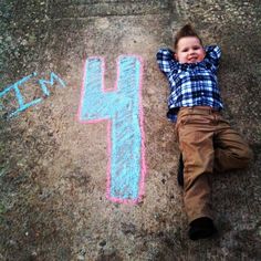 a little boy laying on the ground next to chalk