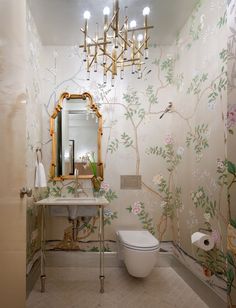 a bathroom with floral wallpaper, toilet and sink in front of a large mirror