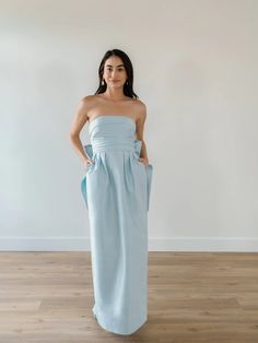 a woman in a strapless blue dress poses for the camera with her hands on her hips