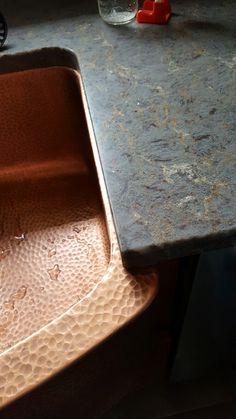 a copper sink sitting on top of a counter next to a red brick oven mitt