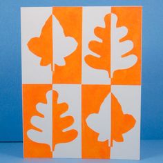 an orange and white card with leaves cut out of it on a blue tablecloth