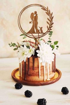 a wedding cake decorated with flowers, berries and an acrylic sign on top