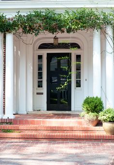 the front entrance to a house with potted plants