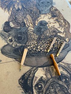 two pencils are laying on the ground next to a drawing with dogs and birds