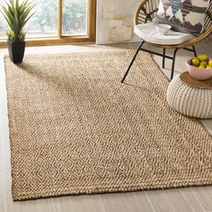 a living room area with a chair, rug and potted plant on the floor