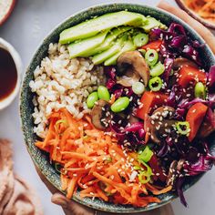 a bowl filled with rice, carrots and other vegetables on top of a table