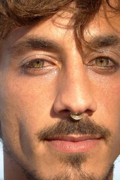 a close up of a man with a nose ring on his nose and mustache piercing