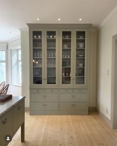 an empty kitchen with wooden floors and glass cabinets in the center, surrounded by white walls